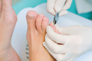 A podiatrist giving nail care to a client.